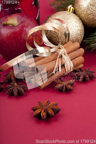 Image of christmas decoration red apple, cinnamon, anise and tree on red background