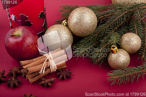 Image of christmas decoration red apple, cinnamon, anise and tree on red background