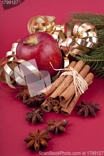 Image of christmas decoration red apple, cinnamon, anise and tree on red background