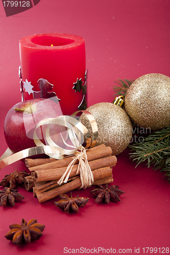 Image of christmas decoration red apple, cinnamon, anise and tree on red background