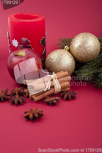 Image of christmas decoration red apple, cinnamon, anise and tree on red background