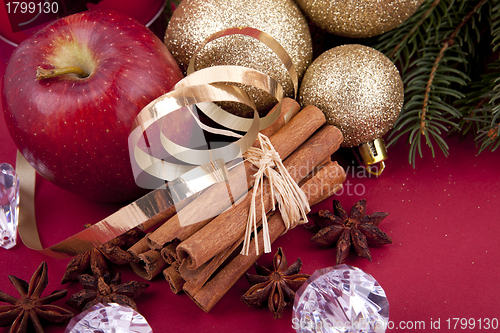 Image of christmas decoration red apple, cinnamon, anise and tree on red background