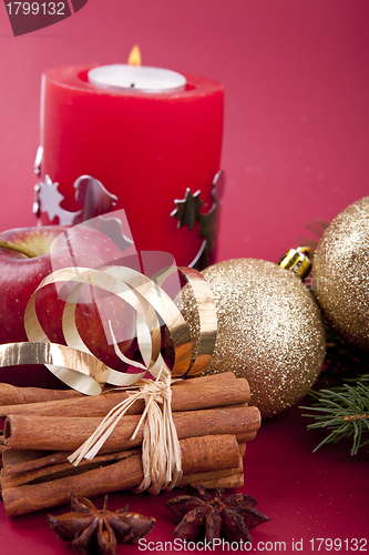 Image of christmas decoration red apple, cinnamon, anise and tree on red background