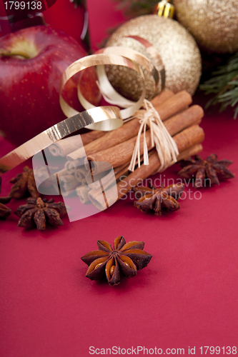 Image of christmas decoration red apple, cinnamon, anise and tree on red background
