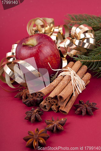 Image of christmas decoration red apple, cinnamon, anise and tree on red background