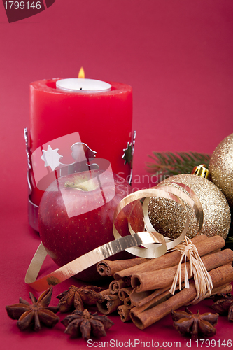 Image of christmas decoration red apple, cinnamon, anise and tree on red background