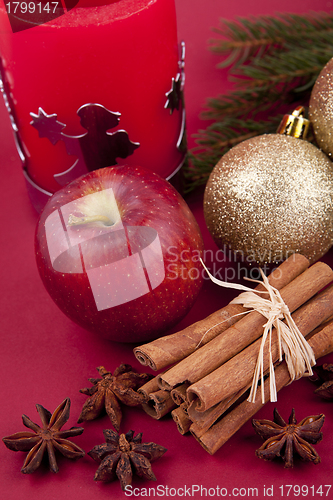 Image of christmas decoration red apple, cinnamon, anise and tree on red background