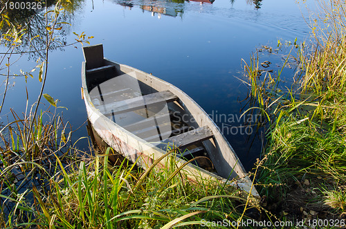 Image of Retro wooden boat on lake shore. water transport 