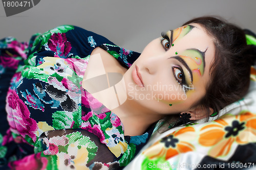 Image of young happy girl lying with beautiful make up on her face