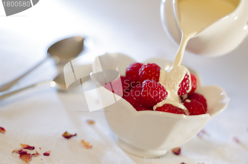 Image of Cream Pouring From a Jug Over Fresh Raspberries