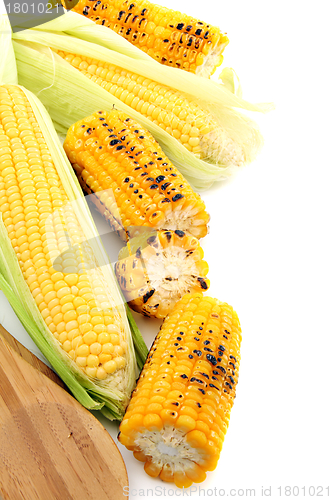 Image of Cleaning freshly roasted ears of corn on cob with green leaves.