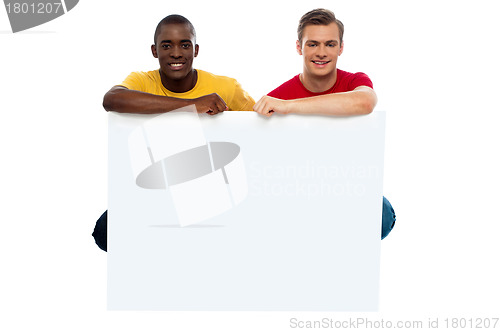 Image of Casual young guys posing with blank billboard