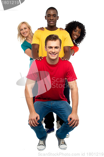 Image of Young people standing behind semi seated guy