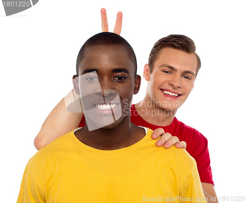 Image of Guy making funny gesture behind his friends head