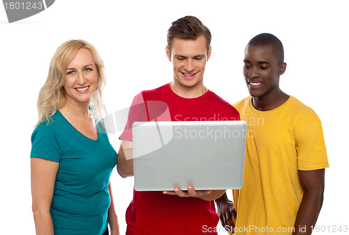 Image of Cheerful group of friends working on laptop