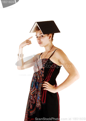 Image of Portrait of girl with book on head.