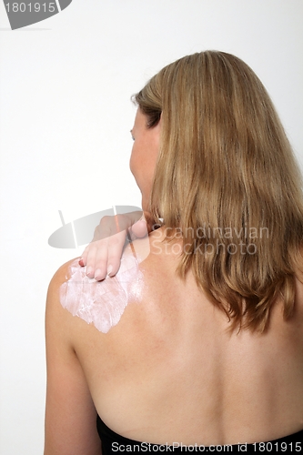 Image of Young woman lotion her back with suncreme