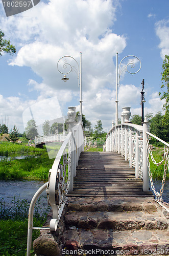 Image of White decorative bridges through park stream sky 