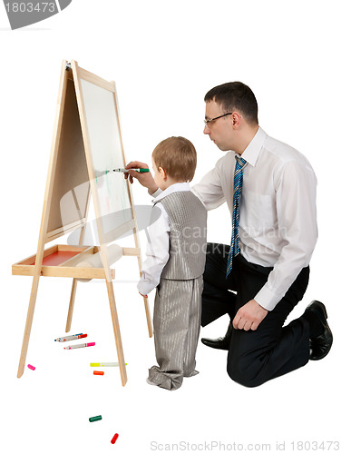 Image of Businessman teaches his son to paint on an easel