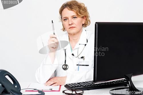 Image of Serious aged doctor posing with pen in hand