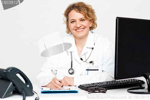 Image of Smiling middle aged female doctor sitting in clinic