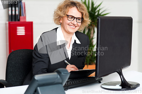 Image of Its time to work. Front desk lady making notes