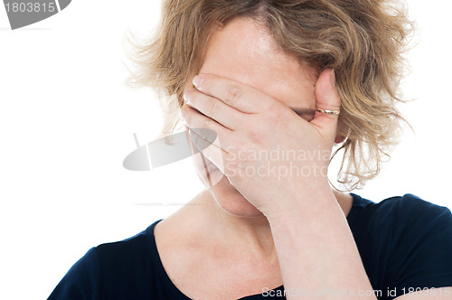 Image of Unhappy woman hiding her face with hand on it