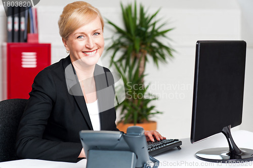 Image of Smiling corporate woman typing on keyboard