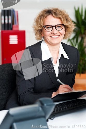 Image of Female executive writing notes on clipboard