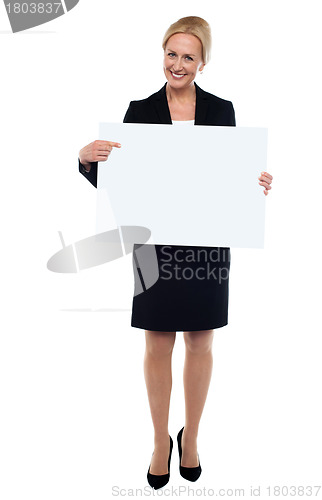 Image of Female executive pointing towards white ad board