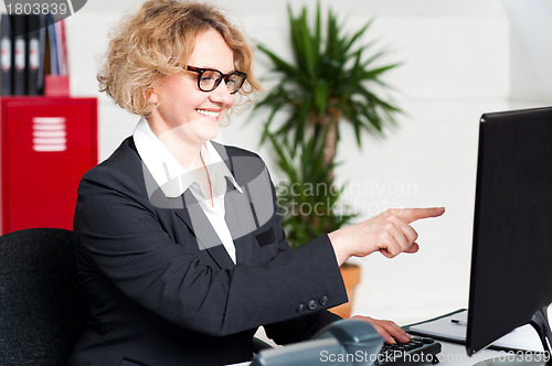 Image of Cheerful woman pointing at computer screen