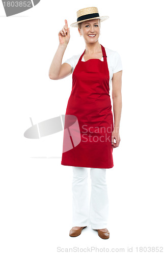 Image of Female chef wearing hat pointing upwards