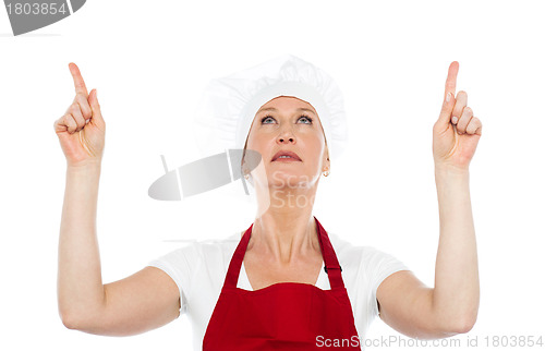 Image of Female chef in uniform pointing upwards