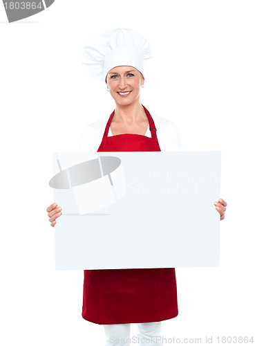 Image of Happy female chef displaying white billboard