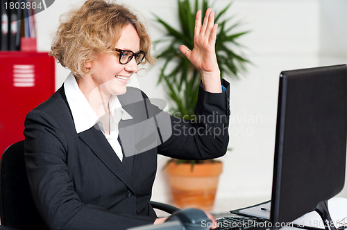 Image of Smiling woman with raised arm looking at screen