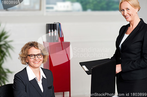 Image of Woman handing over files to her female boss