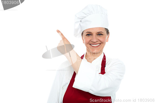Image of Aged woman chef pointing at copy space area