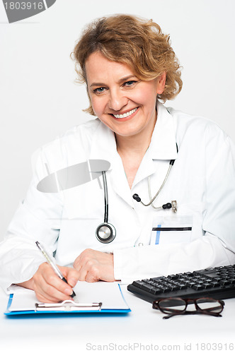 Image of Happy female physician at work desk