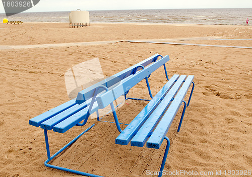 Image of Blue bench and bathing-box on seaside beach sand 