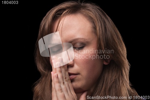 Image of Young woman is in praying against dark background