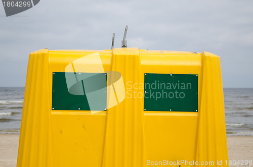 Image of Closeup of yellow waste bin container on sea beach 