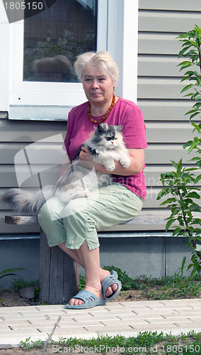 Image of Woman on a summer residence with a cat on hands
