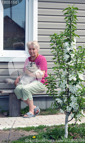 Image of Woman on a summer residence with a cat on hands