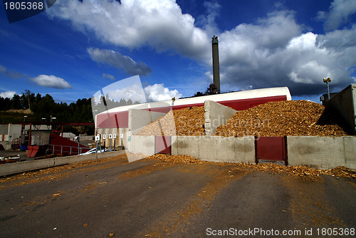 Image of bio power plant with storage of wooden fuel against blue sky