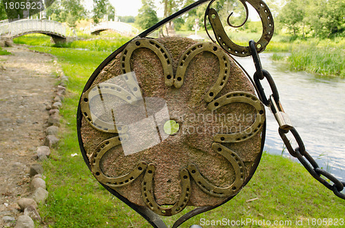 Image of Horse shoes on old millstone and chain in park 