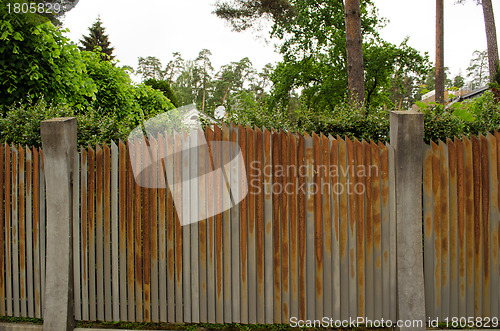 Image of Old rusty steel metal fence arround house yard 