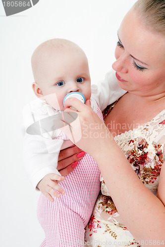 Image of baby with a pacifier in the arms of mother