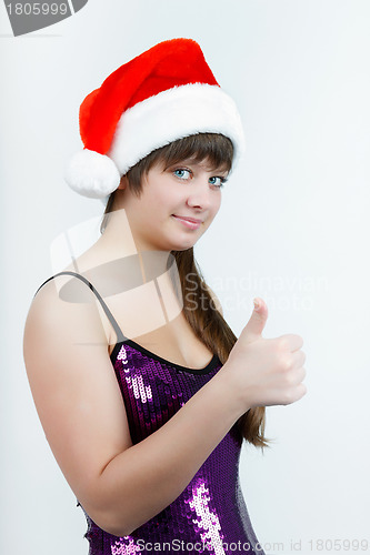 Image of attractive girl in a Christmas hat with thumb up