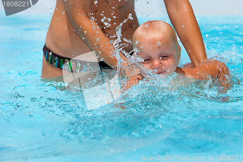 Image of Child having fun in water with mom. 