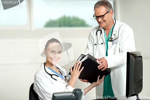 Image of Male doctor handing over files to female doctor